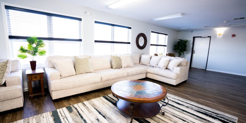 A bright and spacious living room with a large, comfortable beige sectional, a stylish coffee table, and plenty of natural light, perfect for relaxation.