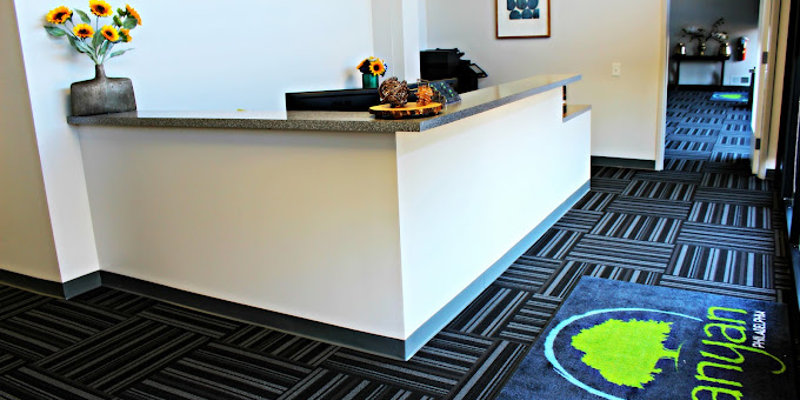  A welcoming reception area with a clean, modern design, featuring bright sunflowers, a gray countertop, and a Banyan-branded entrance mat.