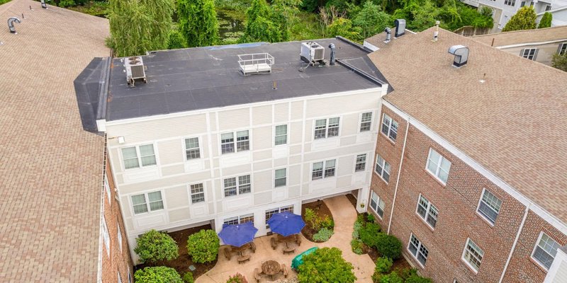  Aerial view of a peaceful recovery center courtyard featuring shaded seating areas, lush greenery, and serene surroundings for relaxation.