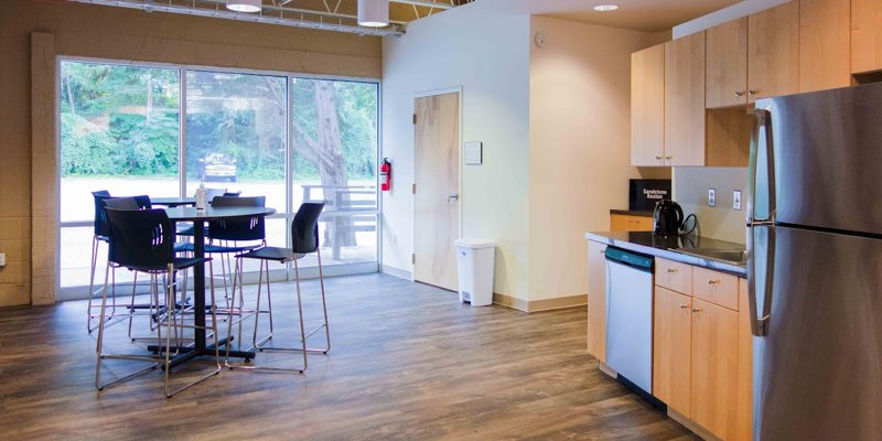 A modern and bright kitchen area with a sleek table, chairs, and stainless steel appliances, creating a warm, welcoming atmosphere for guests.