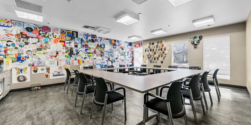 Bright and engaging art therapy room with vibrant walls showcasing creative artwork and masks, offering a space for expression and healing.