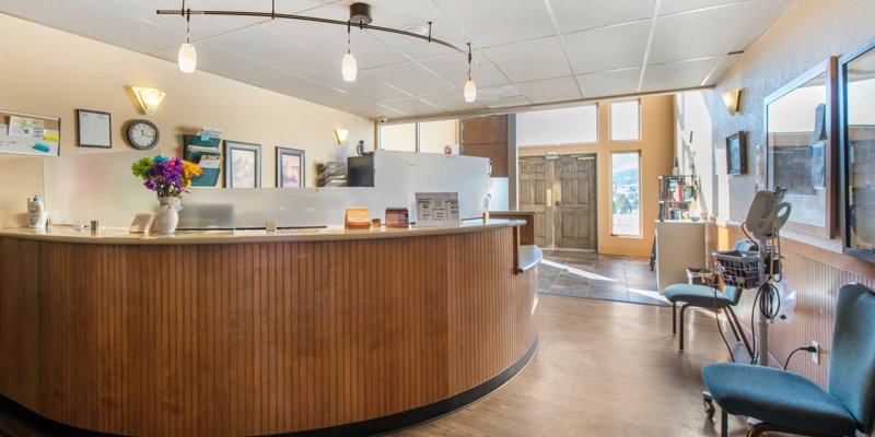 A welcoming reception area with warm lighting, a curved wooden desk, and colorful flowers, creating a friendly and inviting first impression.