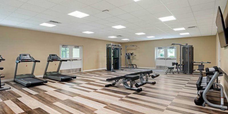  A spacious, well-lit gym with treadmills, strength machines, and free weights provides a welcoming space for fitness and wellness activities.