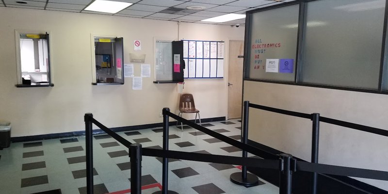 A well-organized waiting area with a checkered floor features partitioned lines for service windows. Signs on the wall provide instructions for visitors.