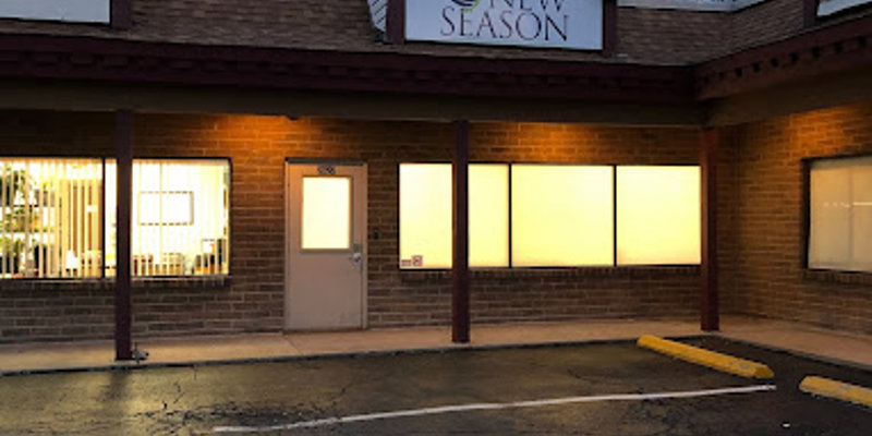 The exterior of the New Season facility is warmly lit during dusk, offering a welcoming and calming atmosphere with ample parking space.