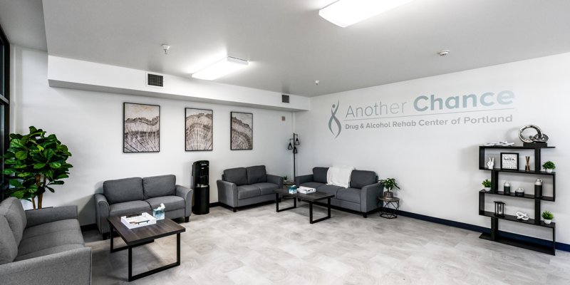 A cozy, welcoming lounge with modern grey couches, soft lighting, framed wall art, and decorative shelves, creating a calming atmosphere.