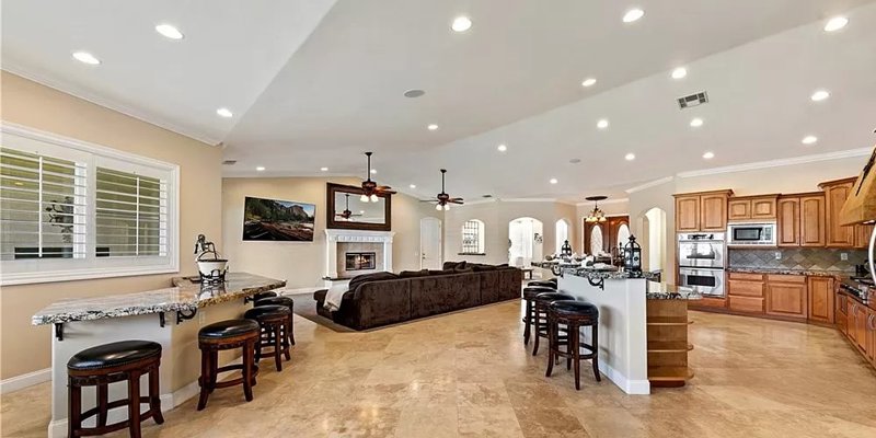  Spacious and bright open-concept living area with a modern kitchen, cozy seating, a fireplace, and elegant bar stools for seating.