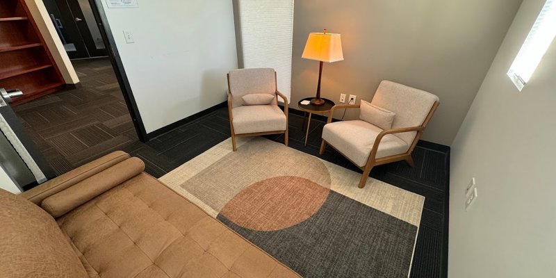 Cozy and private therapy room with soft lighting, comfortable chairs, and a stylish rug, creating a warm and inviting space for conversations.