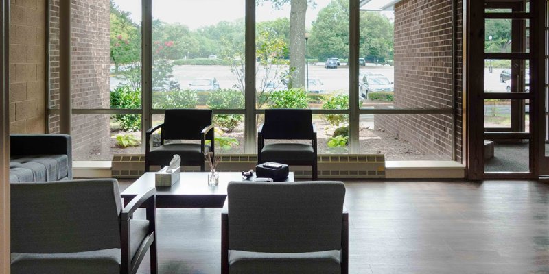 A cozy and modern sitting area with comfortable chairs and a large window offering a relaxing view of greenery and natural light.