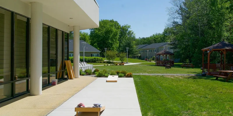 Peaceful outdoor space with a sunny patio, lawn games, gazebos, and lush greenery, ideal for relaxation and recreational activities.