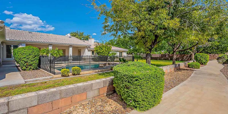 A beautifully landscaped backyard with a pool surrounded by lush greenery, offering a serene and inviting space for relaxation.