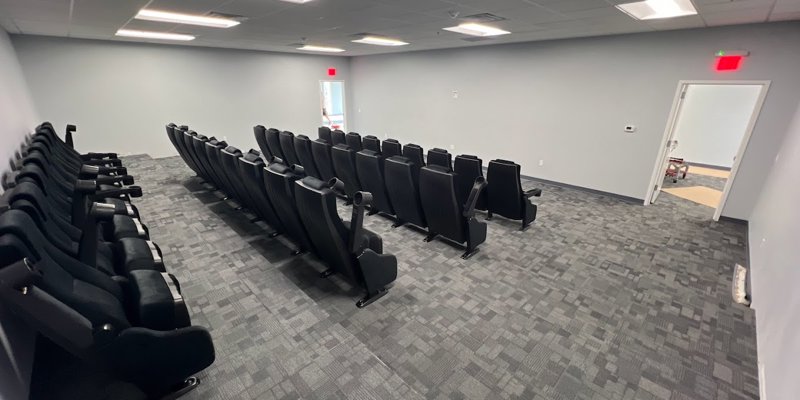  A spacious room with comfortable, theater-style seating, bright lighting, and neutral tones, designed for group sessions or presentations.