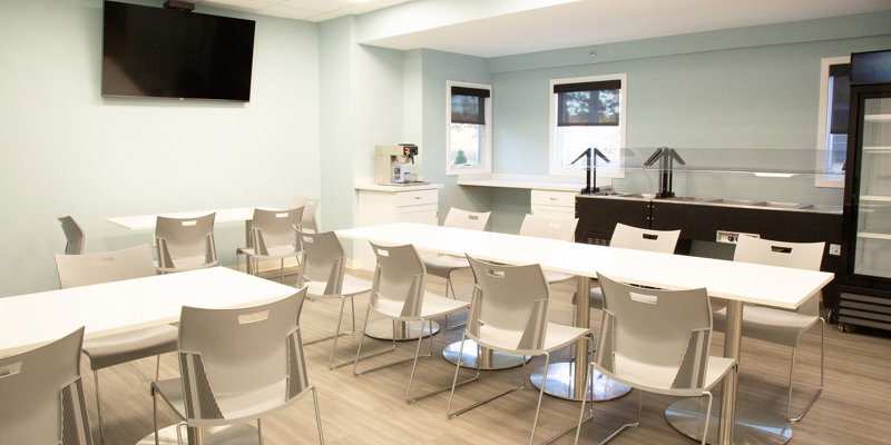 A bright and clean dining area with modern seating, a large TV, and a buffet-style setup, creating a comfortable and inviting space for meals.