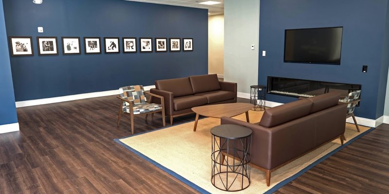 Cozy seating area with modern furniture, a wall-mounted TV, and a fireplace, complemented by artistic black-and-white photographs.