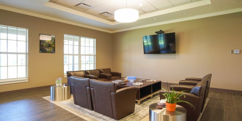 A comfortable lounge area with leather seating, a large TV, and soft lighting. The space feels cozy and inviting, perfect for relaxation or conversation.