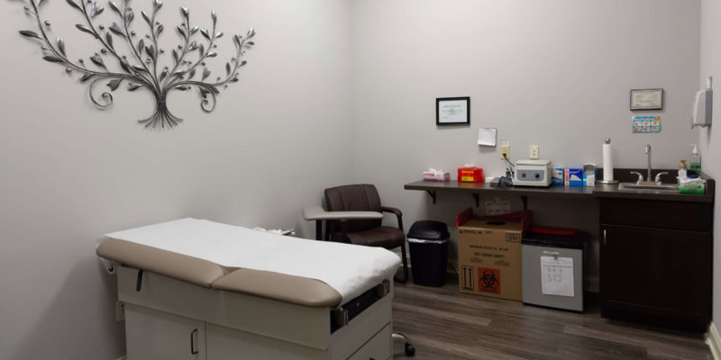 A clean and organized medical exam room features an exam table, comfortable seating, and modern equipment, offering a calming atmosphere.