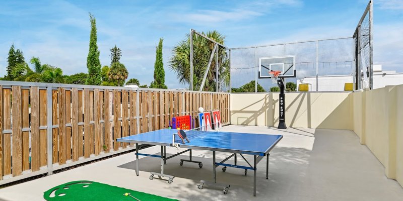 An outdoor recreational area featuring a basketball hoop, ping pong table, and mini putting green, offering a fun and active space for relaxation.