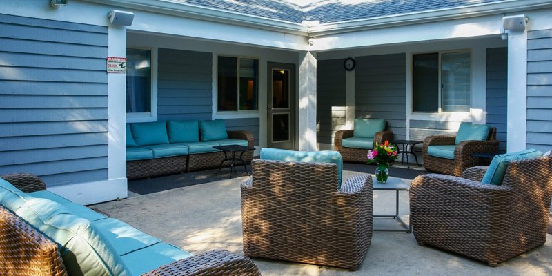 An inviting outdoor seating area with wicker furniture and teal cushions. Surrounded by a calm atmosphere, perfect for relaxation or conversation.