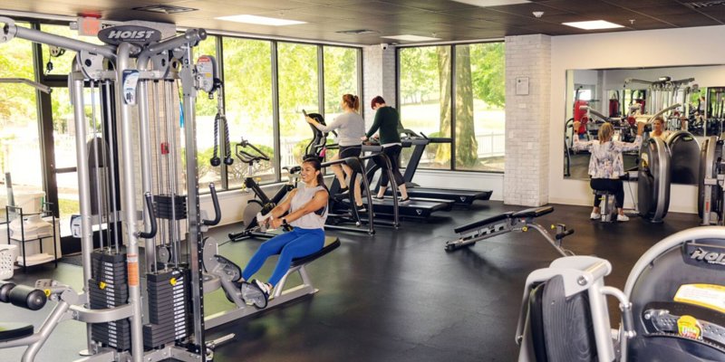 Modern fitness center with large windows, natural light, and various exercise equipment, offering a bright and motivating space for workouts.