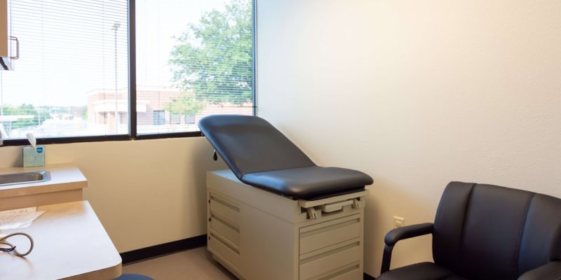 A bright, clean exam room with natural light, a comfortable exam table, and a chair, creating a welcoming environment for patients.