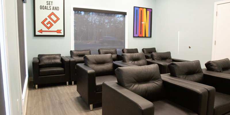 A cozy lounge area with comfortable black chairs and motivational artwork, creating a relaxing and inspiring environment for group discussions or leisure.