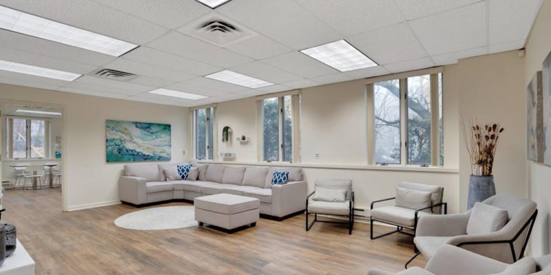 A spacious living area with a large L-shaped couch and several comfortable chairs, designed for group sessions or relaxation.