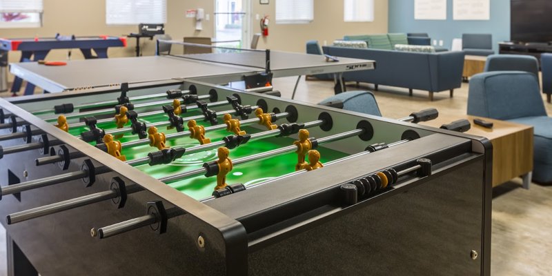 A vibrant recreation room with a foosball table, ping pong, and comfortable seating areas, providing a lively and engaging space for relaxation.