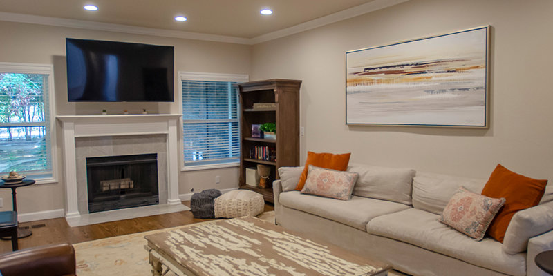 A warm, inviting living room with a cozy fireplace, plush sofas with colorful cushions, a rustic coffee table, and a mounted TV, perfect for relaxation.