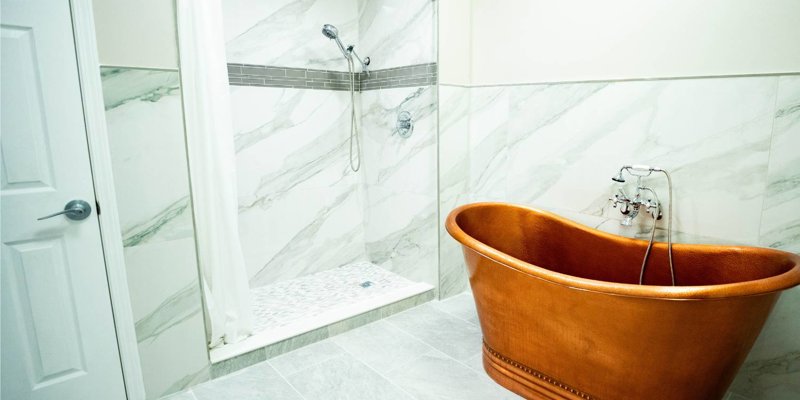 Elegant bathroom with a luxurious copper soaking tub, marble-tiled walls, and a spacious walk-in shower with modern fixtures.