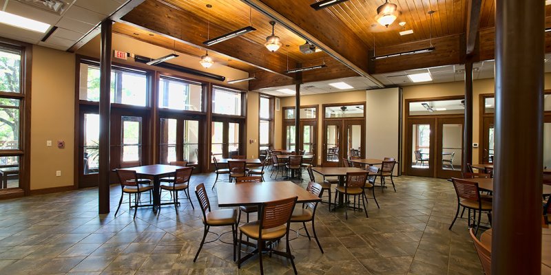  Spacious dining area with warm wood accents, ample natural light, and multiple seating arrangements, creating an inviting atmosphere.