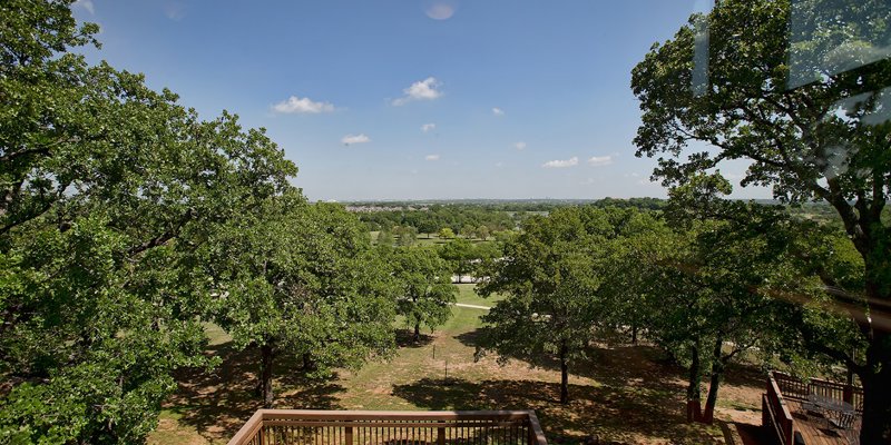 Expansive view of lush green trees and open fields, with a cozy deck for outdoor seating, perfect for enjoying the serene natural surroundings.