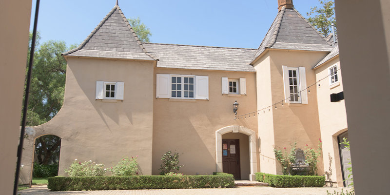  Charming, castle-like building with a cobblestone courtyard, arched entryway, and picturesque turrets, creating a serene and enchanting atmosphere.