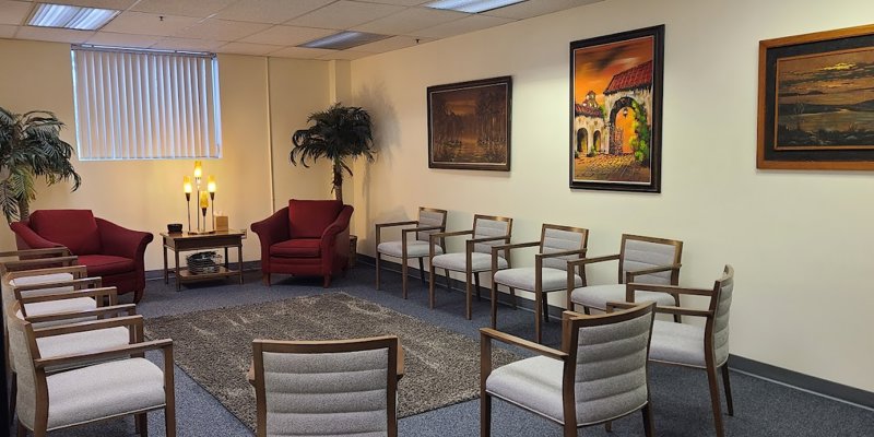 A warm and inviting meeting room with comfortable chairs arranged in a circle. Art, plants, and soft lighting create a cozy, welcoming atmosphere.