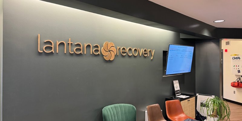 Modern and welcoming reception area at Lantana Recovery with stylish decor, comfortable seating, and a neatly displayed sign on a dark wall.