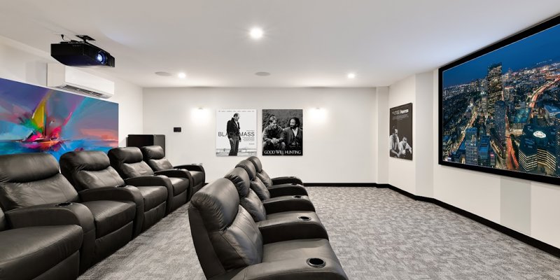  Luxurious home theater with plush leather recliners, a large screen showing a vibrant cityscape, and movie posters adorning the walls.