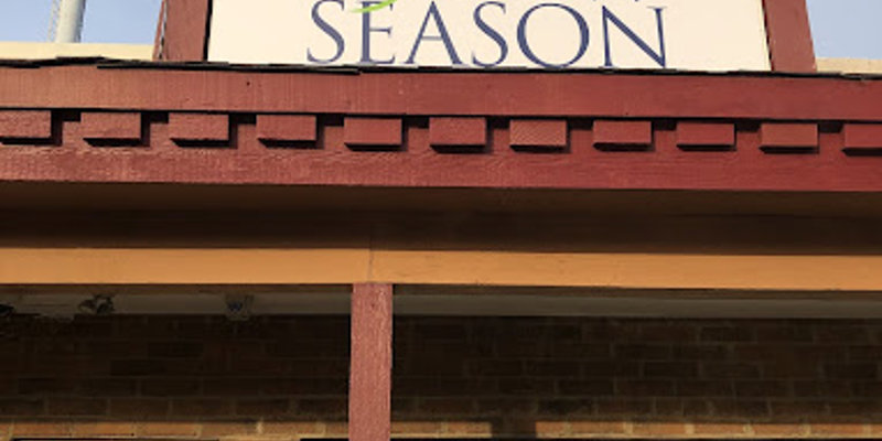  A bright sign with the "New Season" logo above a welcoming entrance to a brick building, showcasing a clean and inviting facility exterior.