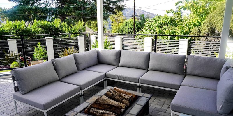  A cozy outdoor lounge area with a modern sectional sofa and firepit, surrounded by lush greenery and scenic mountain views for relaxation.