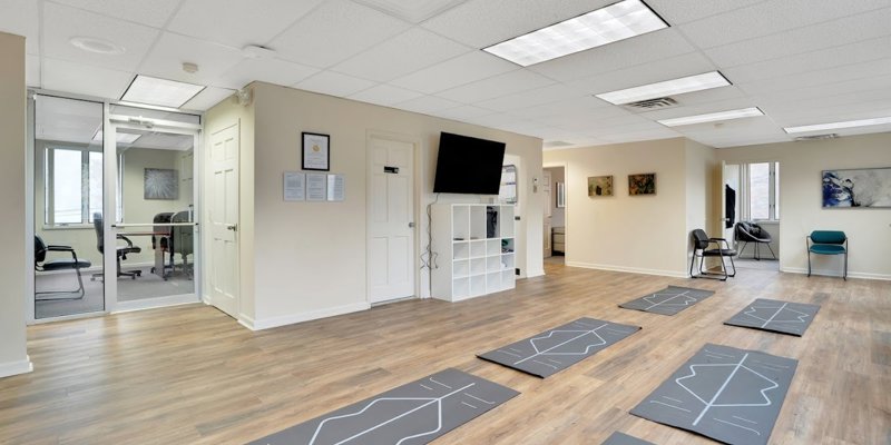 A bright and clean yoga room with mats neatly arranged, providing a peaceful space for meditation and physical wellness practices.