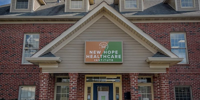  A welcoming brick building with a sign reading "New Hope Healthcare Institute" above the entrance, set against a bright, blue sky.