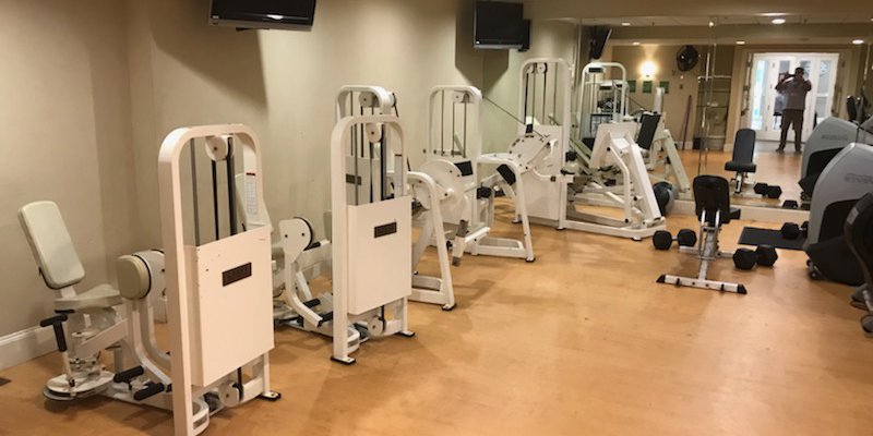 Well-equipped fitness room with various exercise machines, free weights, and spacious layout, promoting physical wellness in a supportive environment.