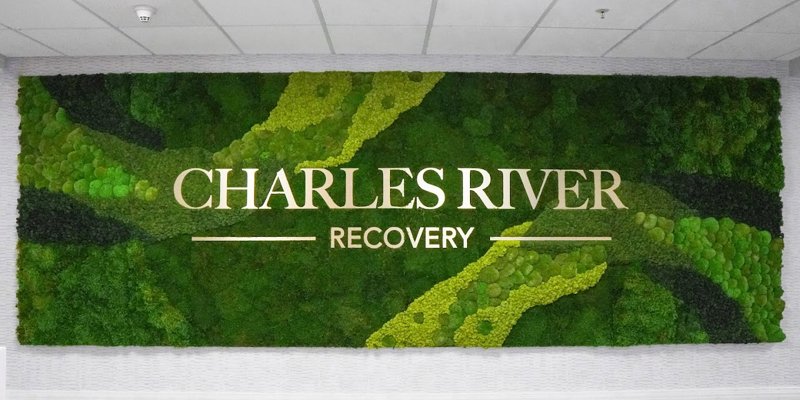 A modern, vibrant green wall display features the words "Charles River Recovery," creating a welcoming and natural ambiance in the space.