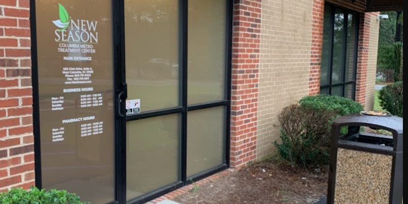 The entrance to a treatment center with frosted glass doors, a brick exterior, neatly trimmed bushes, and a clean, welcoming walkway.