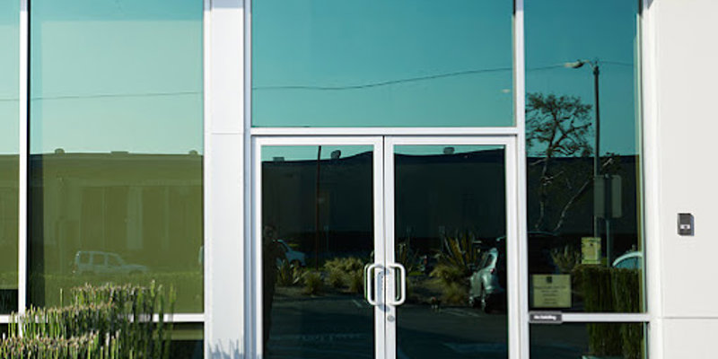 A modern entrance with large glass doors and windows, featuring clean lines and a bright, professional look, creating a welcoming atmosphere.