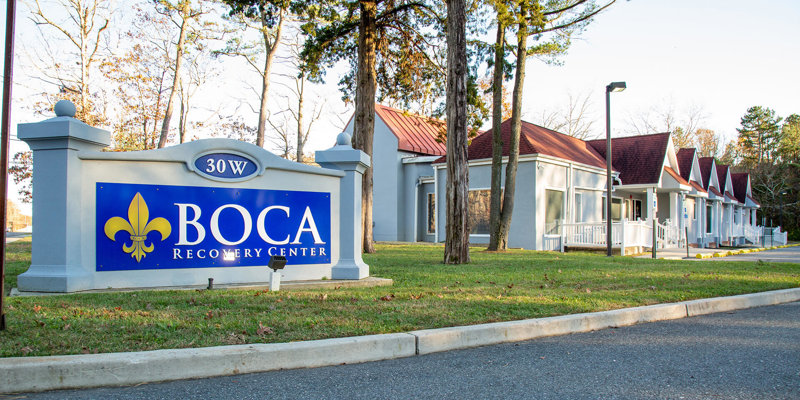 A welcoming entrance to Boca Recovery Center with clear signage, charming buildings, and surrounding trees, creating a peaceful setting for care.