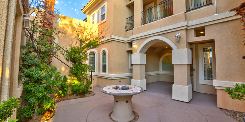  Elegant courtyard with arched entrances, greenery, and a central round fire pit, creating a serene and inviting outdoor space for relaxation.