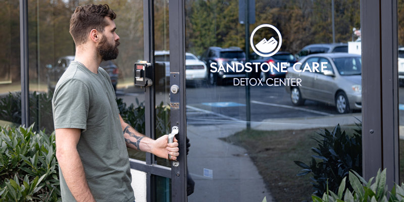  A man confidently enters the Sandstone Care Detox Center, reflecting a sense of hope and determination in a welcoming, supportive environment.