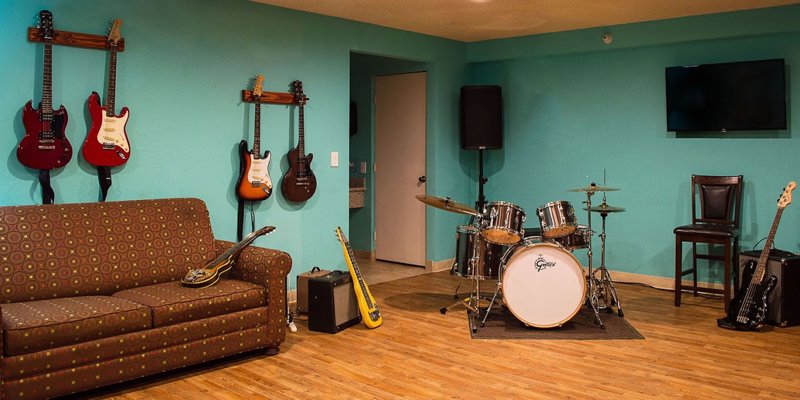 A vibrant music room with guitars, a drum set, and a cozy couch offers a creative space for relaxation and artistic expression.