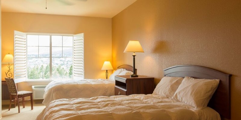 A peaceful bedroom with two cozy beds, soft lighting, and a large window offering serene views, creating a calm and restful environment.