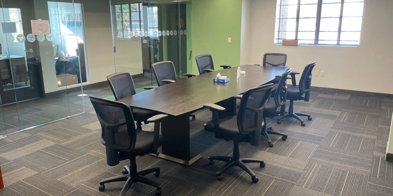  A modern conference room with a large table, ergonomic chairs, glass walls, and ample natural light, creating a professional and collaborative workspace.