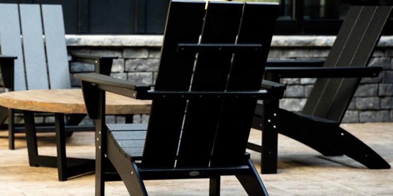 Modern outdoor seating area with sleek black Adirondack chairs and a wooden table, perfect for relaxing and enjoying fresh air.